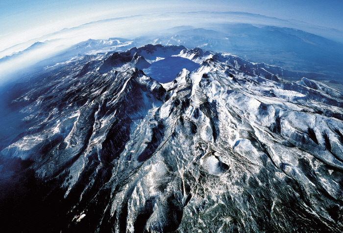 ‘백두산06’(150×220㎝). 하늘에서 바라본 백두산은 신비한 등줄기와 골짜기가 웅건하게 드러나고 있다. 북한이 1987년 출판한 <백두산전설집>은 백두산을 “조종의 산일 뿐 아니라 조선의 신성한 정기가 이는 성산”이라고 썼다. 안승일 작가 제공